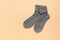 Two warm gray knitted socks on a light beige background. Minimal footwear concept