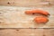 Two washed non-standard carrot are lying horizontally on inverted tree bark.