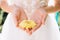 Two wedding rings on the yellow flower of chrysanthemum with tender elegant hands on a wedding-dress under the rays of sunlight.