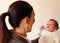 Two weeks old smiling little baby hold by his mother`s hands