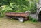 A two-wheeled farm cart parked alongside an arched bridge.