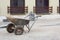 Two-wheeled wheelbarrow on a construction site of a granite pavement with grey regular and even stone blocks