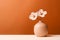 Two white anemone flowers in a peach fuzz color vase on minimal orange copy space background. Modern trendy tone hue shade