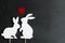 Two white bunnies silhouettes in love on natural stone background