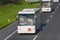 Two white buses on the highway at sunny day