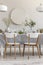 Two white chairs standing by the table with fresh plants and glass vessels