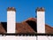 Two white chimneys on the roof against blue sky