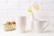 Two white coffee latte and cappuccino mug mockup with soft yellow orchid in vase and cookies in wicker basket