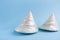 Two white conical mother-of-pearl shells on blue background.