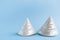 Two white conical pointed mother-of-pearl seashells on light blu