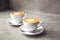 Two white cups of tasty cappucino with love art latte