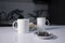 Two white cups of tea next to used tea bags next to gingerbread cookies on a white table in a gray kitchen