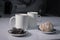 Two white cups of tea next to used tea bags next to gingerbread cookies on a white table in a gray kitchen