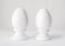 Two white decorative ceramic eggs on a stand or in egg-cups on white background. Easter religious Christian symbol. Easter figurin