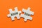 Two white details of puzzle with text know how on orange background, close up