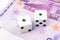 Two white dices with black dots are laying on 500 euro banknote