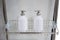 Two white dispenser bottles on metal bathroom shelf
