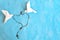 Two white dove origami carrying rosary or scapular in sky blue background.