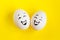 Two white eggs on yellow background concept. Emotions laughter and happiness.