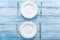 Two white empty plates and cutlery on blue table.