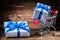 Two white giftboxes and shopping cart on vintage wood