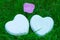 Two white glossy porcelain hearts and a flower on green grass; Summer. Wedding card; A love note. Copy space