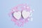 Two white heart on pastel blue background with scattered pink glitter stars. Love concept for your design