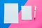 Two white mockup blanks and pen on geometric pink and blue background.