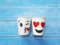 Two white paper cups with face kiss and smile on wood table.