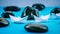 Two White Paper Ships in Sigle File between Abstract Black Rock Stones on Blue Background. Side Shot