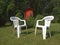 Two white plastic chairs stand on the lawn