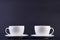 Two white porcelain teacups on dark background show clean and simple design ideas.