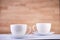 Two white porcelain teacups on wood texture surface show clean and simple design ideas. Selective focus