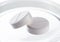 Two white round medical pills on white background