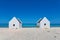 Two white slave houses on beach with blue sea