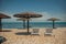 two white sun loungers under a wooden beach umbrella on a rocky beach in summer on a clear day without people