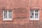 Two white wooden sash windows on a restored red brick wall of a