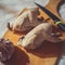 Two whole boiled quails lie on a cutting board as an example of diet food