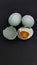 two whole salted duck eggs, one egg split and the shell empty