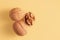 Two whole walnuts and one split walnut on yellow background with free space