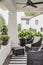 Two wicker chairs and pots of plants on the front porch of a historic craftsman house with blurred neighboring luxury home in back