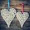 Two wicker hearts hanging on old wooden wall.