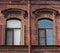 Two windows and drainpipe, on red brick wall