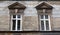 Two windows on the facade of the old ragged brick building