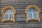 Two windows with wooden carved platbands on a timbered wall