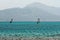 Two windsurfers, blue sea and mount background