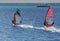 Two windsurfers on sailboards are moving at a speed along the se