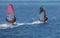 Two windsurfers on sailboards are moving at a speed along the se