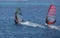 Two windsurfers on sailboards are moving at a speed along the sea surface