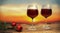 Two wine glasses filled with red wine with two red roses during sunset